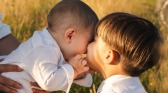 Little Boy kissing his younger brother's cheeks