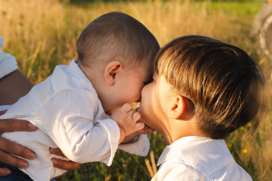 Little Boy kissing his younger brother's cheeks